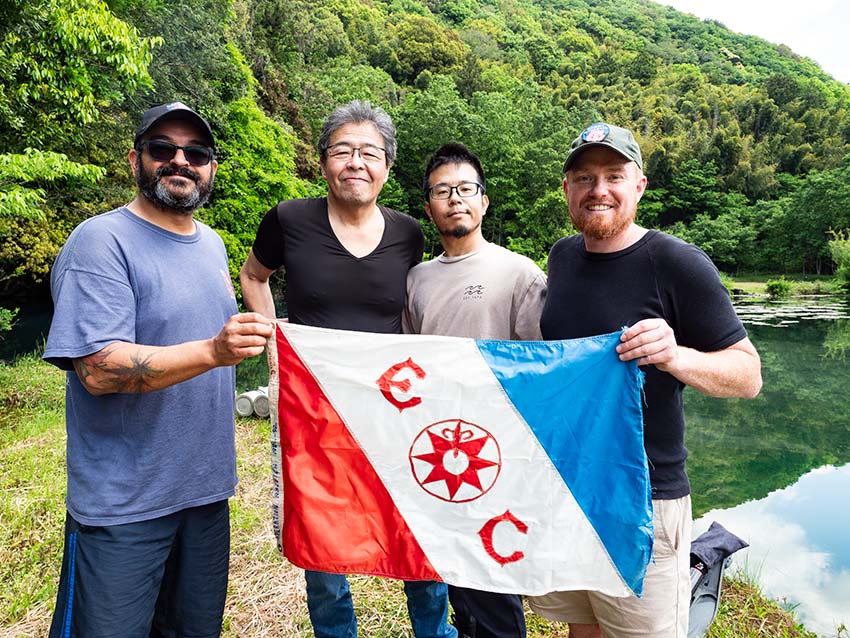 白水の池の前にて、The Explorers Club（エクスプローラーズクラブ）の旗を掲げて